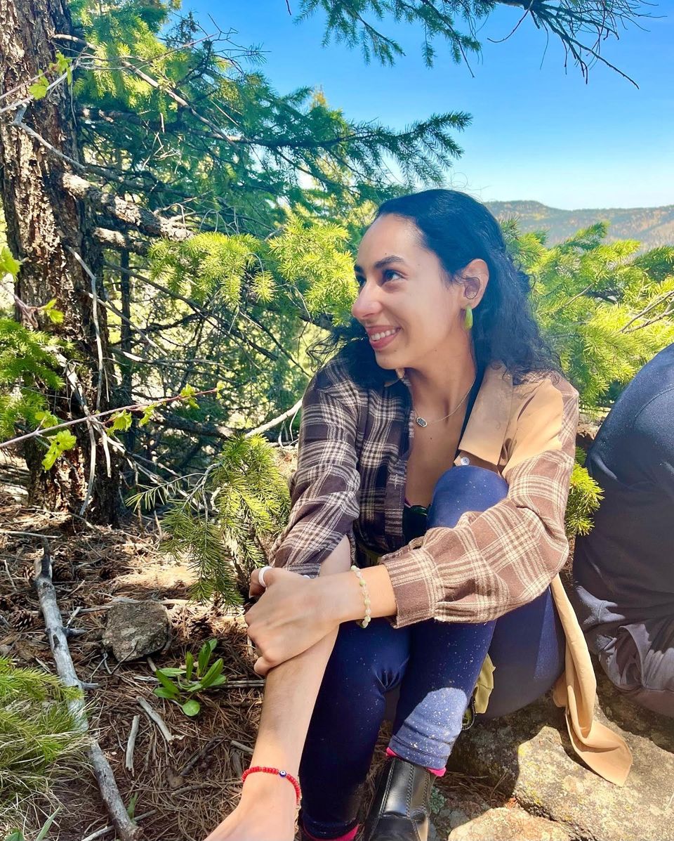 Ariana sitting in a pine forest