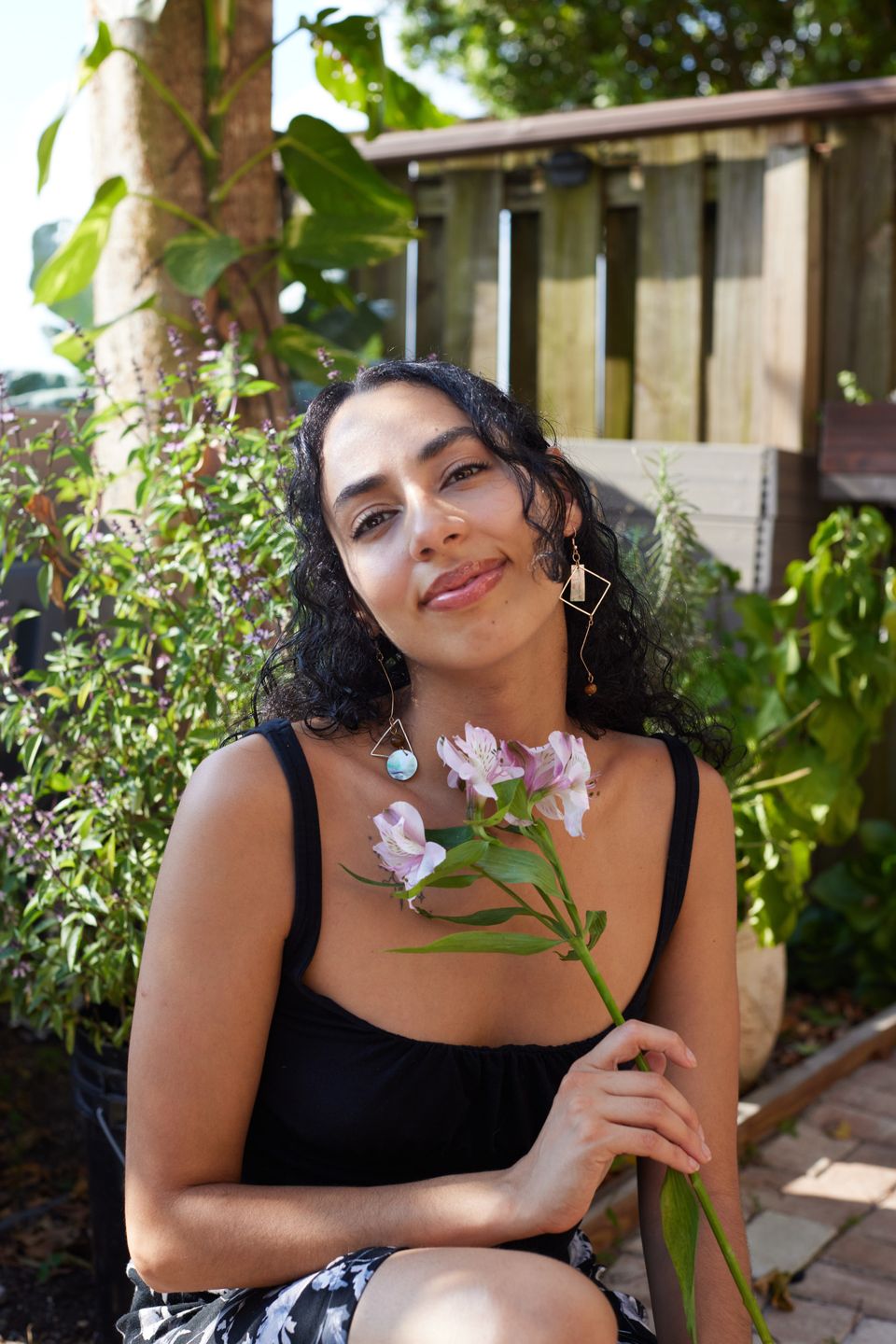 Ariana in her garden holding a flowering stem